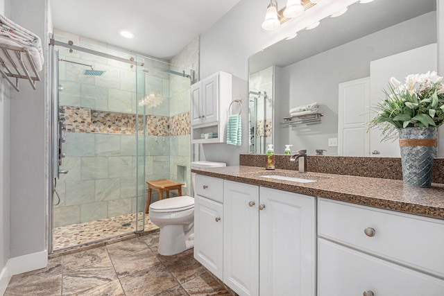 bathroom with toilet, a stall shower, and vanity