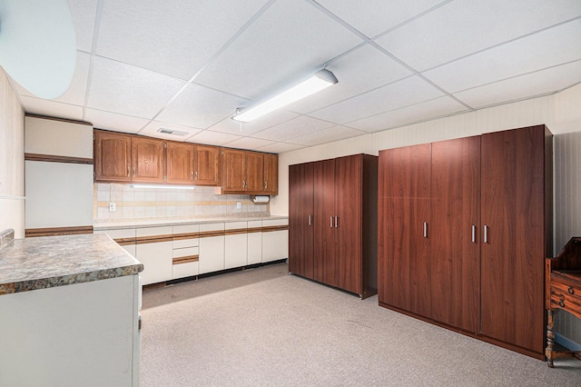 kitchen with visible vents, a drop ceiling, brown cabinets, light countertops, and backsplash