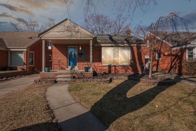 view of front of home with a front lawn, brick siding, and a chimney