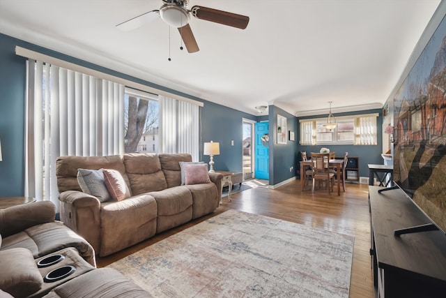 living room featuring baseboards, a ceiling fan, and wood finished floors