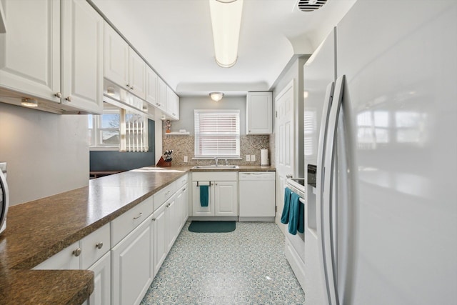 kitchen featuring a sink, white appliances, tasteful backsplash, and white cabinetry