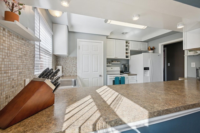 kitchen with a sink, white appliances, a peninsula, and open shelves