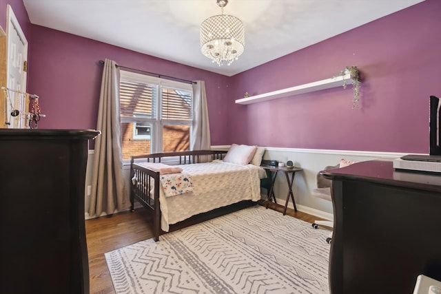 bedroom featuring an inviting chandelier, wood finished floors, and baseboards