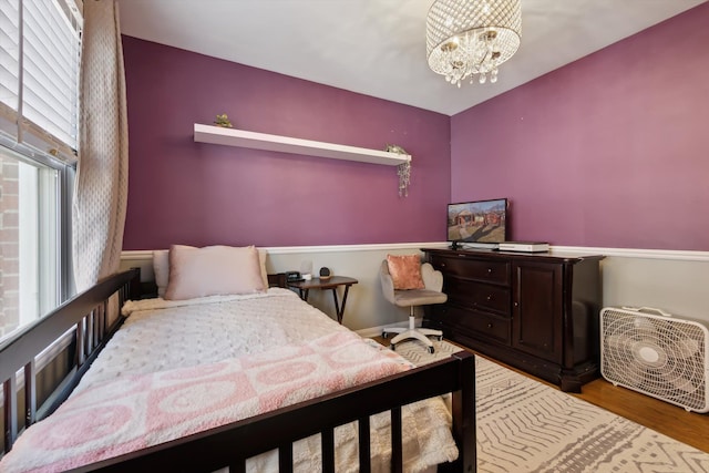 bedroom with wood finished floors and a chandelier