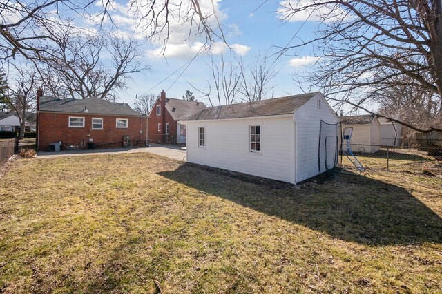 rear view of house featuring an outbuilding, a lawn, a fenced backyard, and a patio area