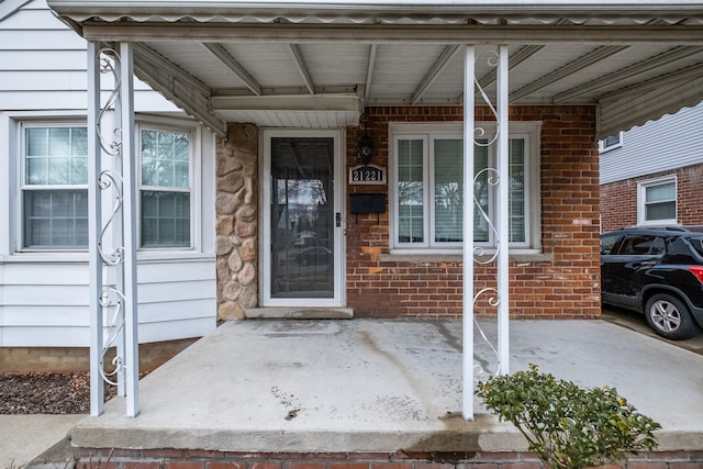 entrance to property with a porch and brick siding