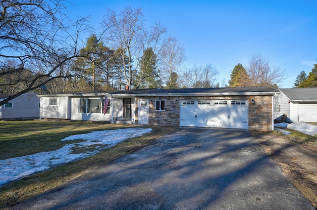 ranch-style house with aphalt driveway, an attached garage, stone siding, and a front yard