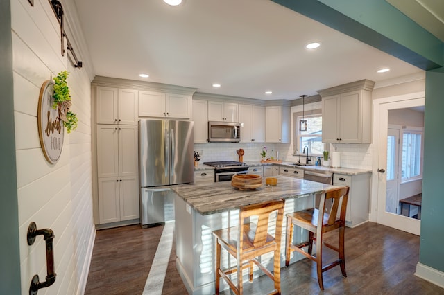 kitchen featuring a breakfast bar, light stone counters, stainless steel appliances, decorative backsplash, and dark wood-style flooring