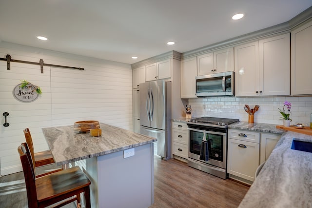 kitchen with tasteful backsplash, light stone countertops, a breakfast bar area, dark wood-style floors, and stainless steel appliances