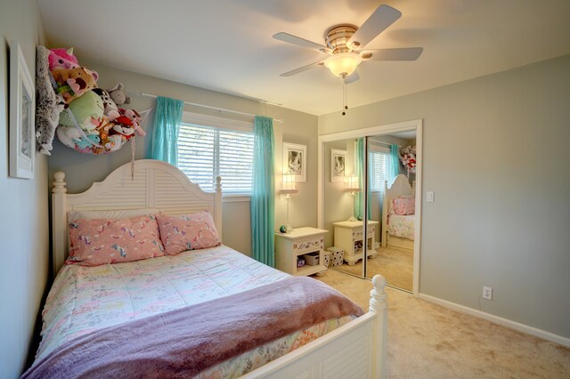 bedroom featuring a closet, light colored carpet, baseboards, and ceiling fan