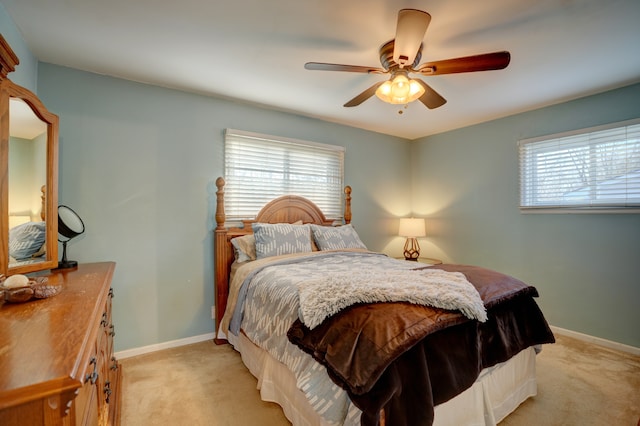 bedroom with a ceiling fan, multiple windows, light colored carpet, and baseboards