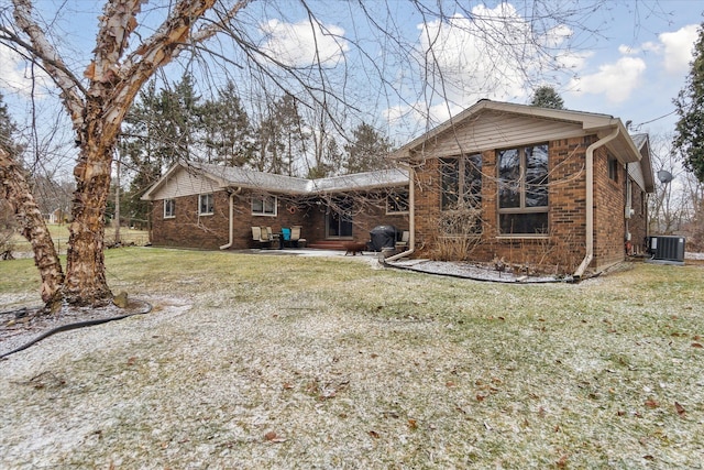 rear view of property featuring brick siding, a lawn, and central air condition unit