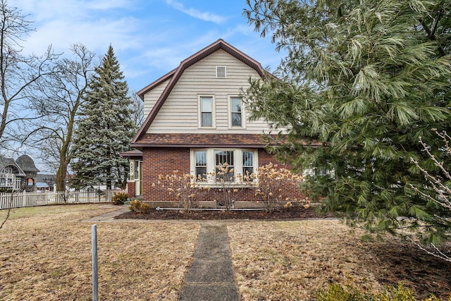 dutch colonial with brick siding, fence, and a gambrel roof