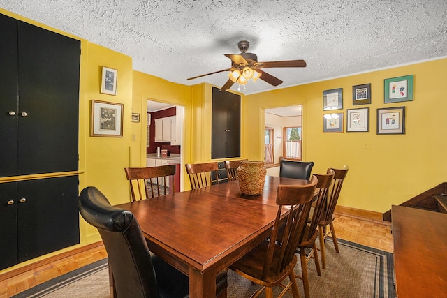 dining room featuring a textured ceiling, a ceiling fan, and baseboards