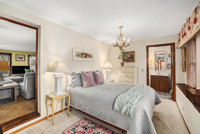 bedroom with light carpet, baseboards, ensuite bath, an inviting chandelier, and a sink