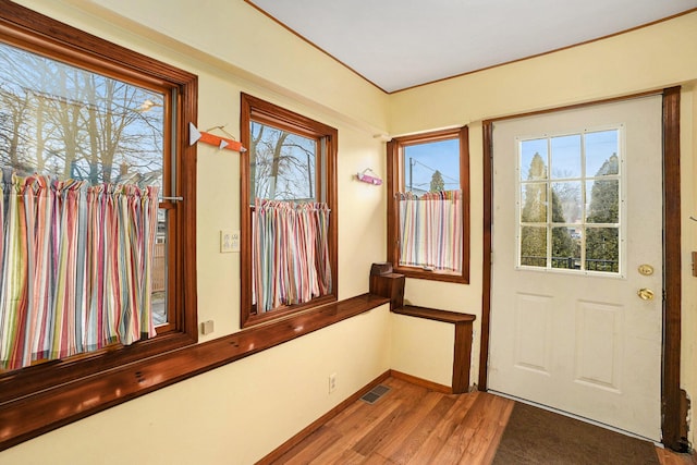 doorway to outside with wood finished floors, visible vents, and baseboards