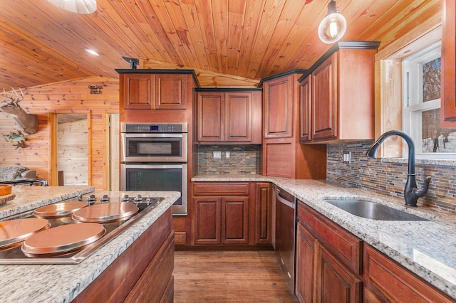 kitchen featuring a sink, vaulted ceiling, stainless steel appliances, light wood-type flooring, and backsplash