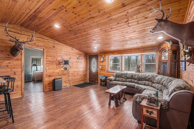 living area with wooden walls, lofted ceiling, wood ceiling, radiator heating unit, and wood finished floors