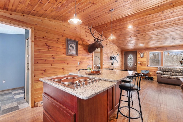 kitchen with a kitchen island with sink, wood ceiling, light wood-style floors, open floor plan, and stainless steel cooktop