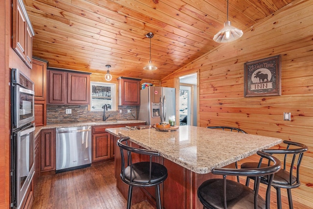 kitchen with dark wood-style floors, a center island, a breakfast bar, stainless steel appliances, and a sink