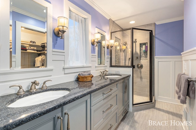 bathroom with a stall shower, ornamental molding, and a sink