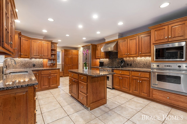 kitchen featuring a sink, appliances with stainless steel finishes, wall chimney range hood, open shelves, and brown cabinetry