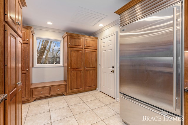 kitchen with stainless steel built in fridge, light tile patterned floors, and brown cabinets