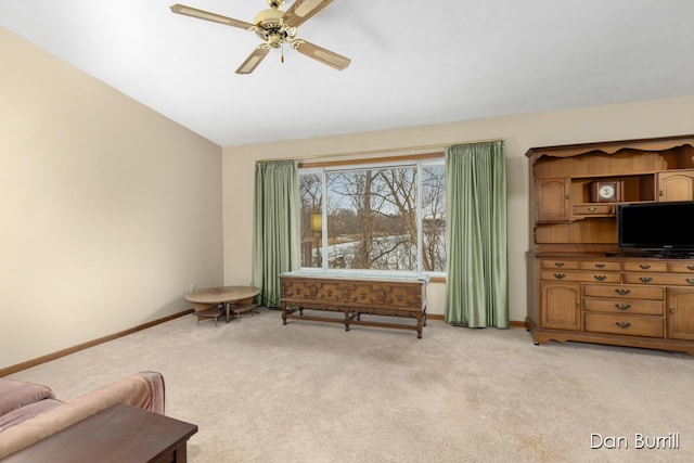 living area with light colored carpet, ceiling fan, and baseboards