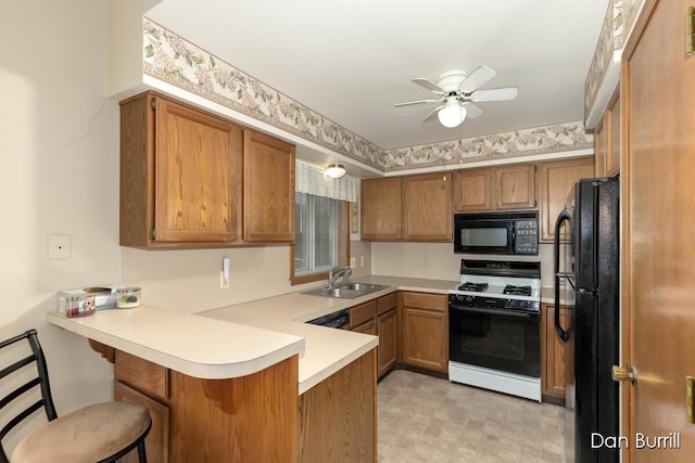 kitchen with black appliances, brown cabinetry, a peninsula, and a sink