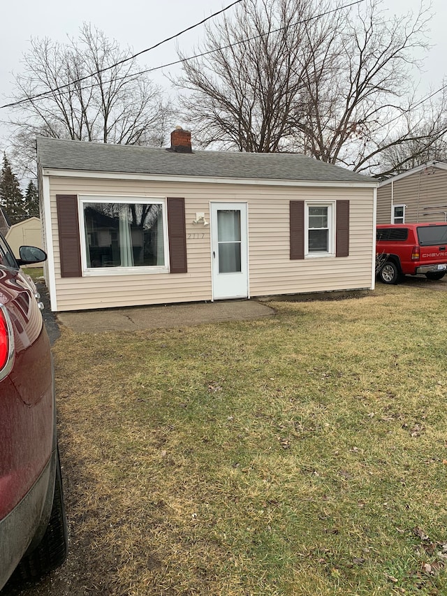 single story home featuring a chimney and a front lawn