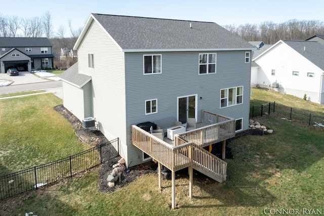 rear view of property with a shingled roof, a lawn, a wooden deck, and a fenced backyard