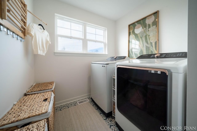 clothes washing area with laundry area, washing machine and dryer, and baseboards