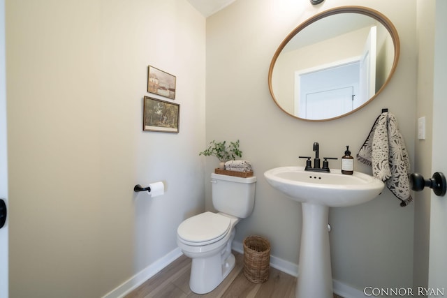 bathroom featuring baseboards, toilet, and wood finished floors