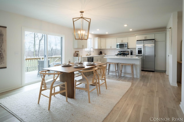 dining room with recessed lighting, baseboards, a notable chandelier, and light wood finished floors