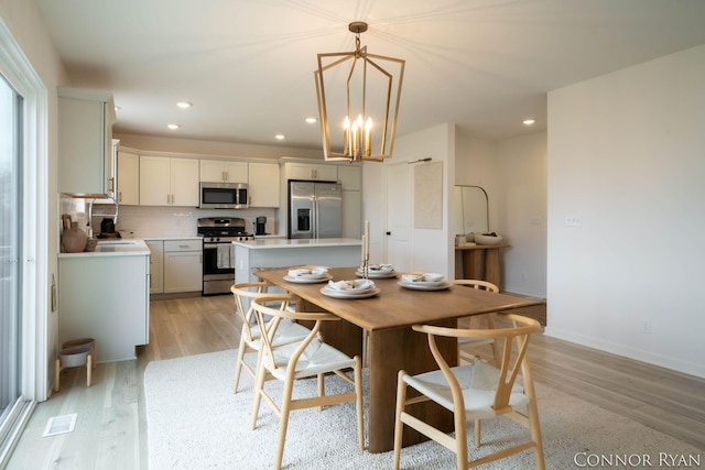 dining room with visible vents, baseboards, light wood-style flooring, an inviting chandelier, and recessed lighting