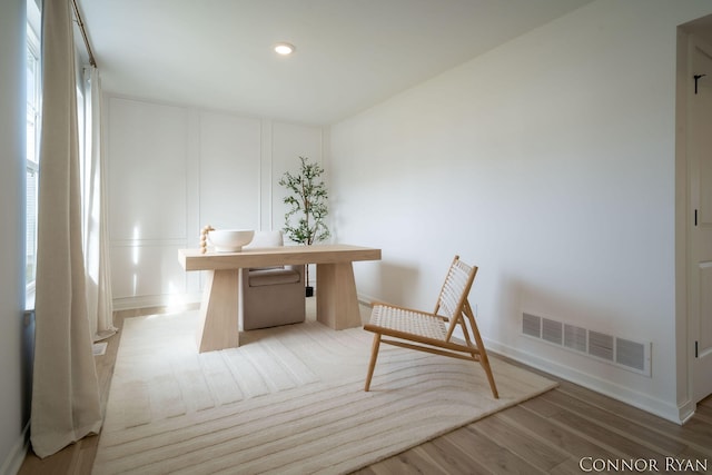 unfurnished office with visible vents, a decorative wall, wood finished floors, and recessed lighting