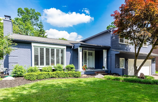 view of front of house with an attached garage, brick siding, a front lawn, and a chimney