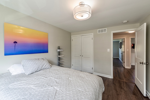 bedroom with baseboards, a closet, visible vents, and wood finished floors