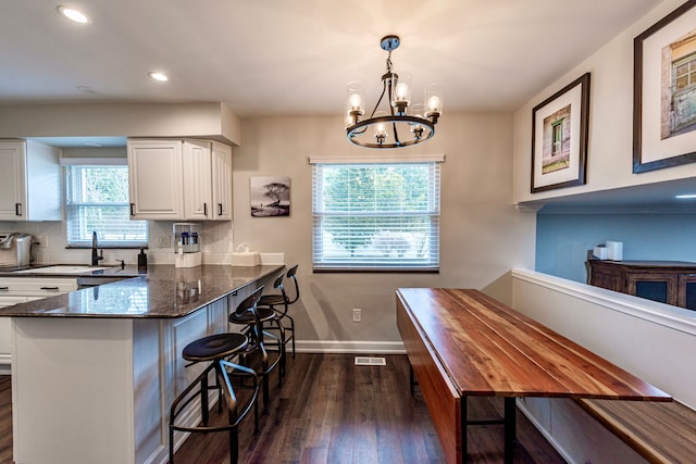 kitchen with baseboards, white cabinets, decorative backsplash, dark wood finished floors, and dark stone countertops