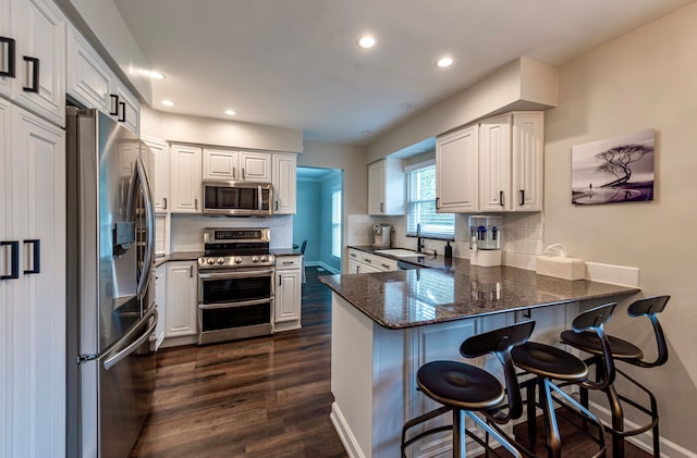 kitchen with stainless steel appliances, dark wood-type flooring, a peninsula, and tasteful backsplash