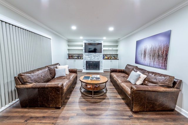 living area featuring wood finished floors, crown molding, built in shelves, a fireplace, and recessed lighting