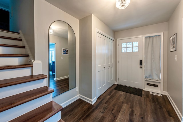 foyer featuring arched walkways, visible vents, stairway, wood finished floors, and baseboards