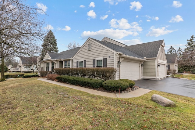 view of front facade featuring an attached garage, driveway, a shingled roof, and a front yard