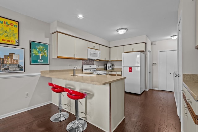 kitchen featuring dark wood-style flooring, light countertops, a sink, white appliances, and a peninsula