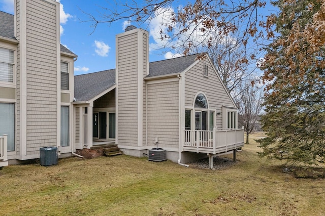 back of property featuring a shingled roof, a lawn, a chimney, and cooling unit