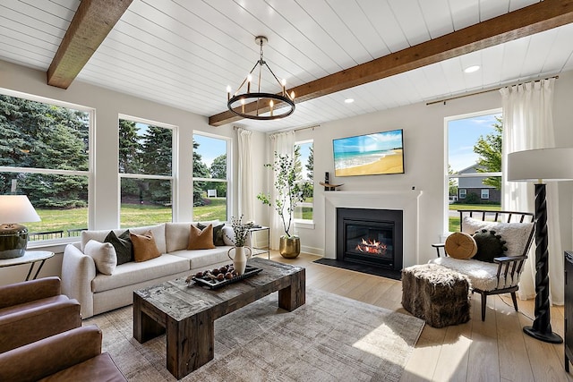 sunroom / solarium with beam ceiling, a glass covered fireplace, and a chandelier