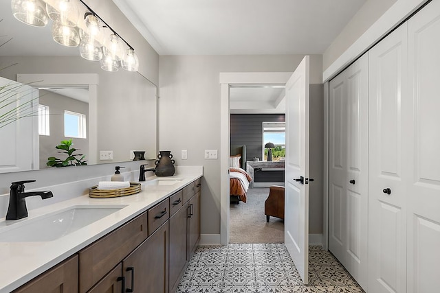 ensuite bathroom featuring double vanity, a healthy amount of sunlight, and a sink