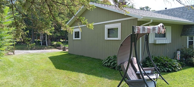 view of side of home featuring a shingled roof and a lawn