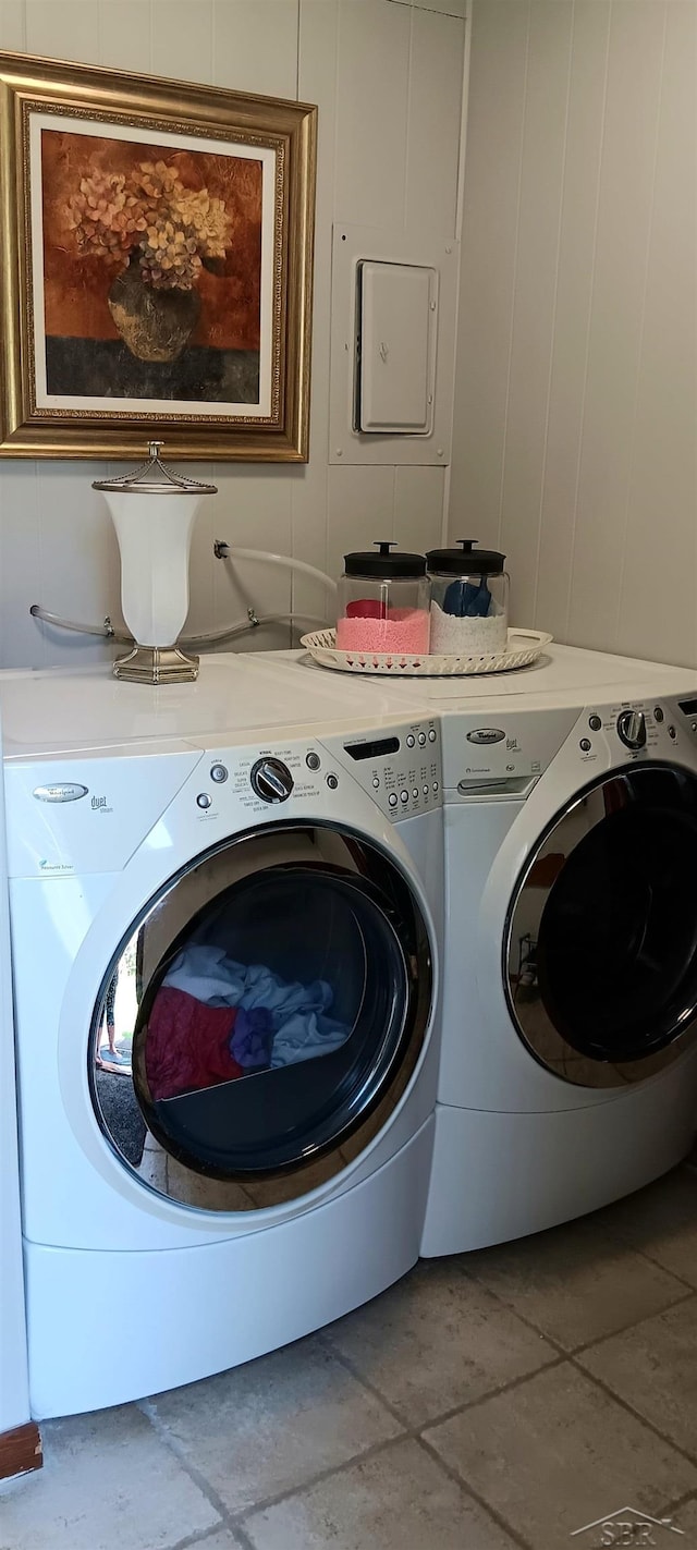 clothes washing area featuring stone finish floor, a decorative wall, and washer and clothes dryer