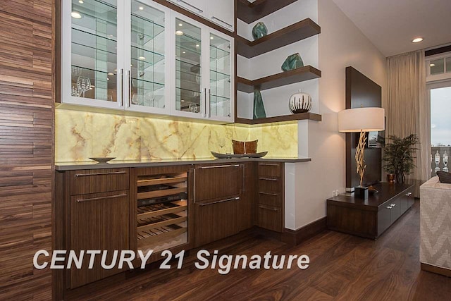 bar with a bar, tasteful backsplash, dark wood-type flooring, and baseboards